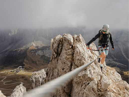 Une grimpeuse encordée progresse sur une arête rocheuse dans la brume