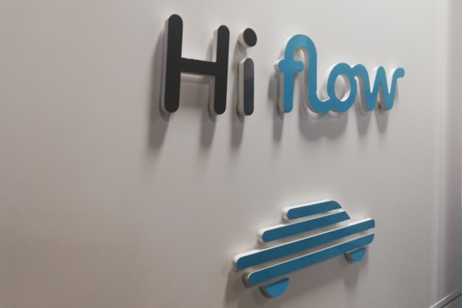 L'enseigne Hiflow en relief sur un mur blanc, au-dessus du pictogramme de la marque