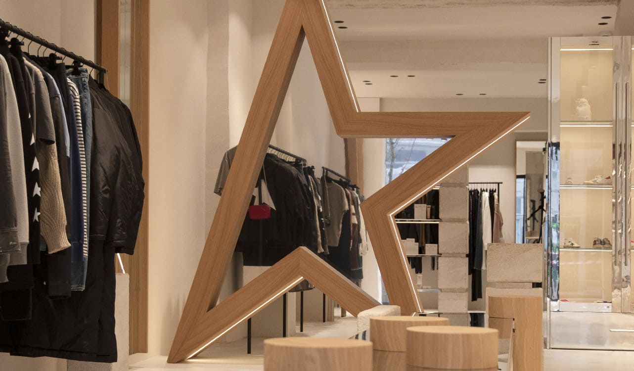 L'intérieur d'une boutique Lulli sur la Toile : une vitrine centrale de maroquinerie et d'accessoires, sous des suspensions en métal patiné